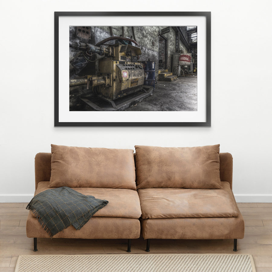 A yellow slurry pump tagged 'Lot 80' with control knobs and pipework in the interior of Awaba Colliery, blue barrels stacked against the wall and a First Aid Station doorway visible in the background.