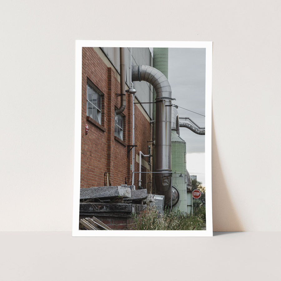 Large curved metal ducting and a cylindrical stack on the exterior red brick wall of the former Bradmill factory at Yarraville, photographed in 2011.