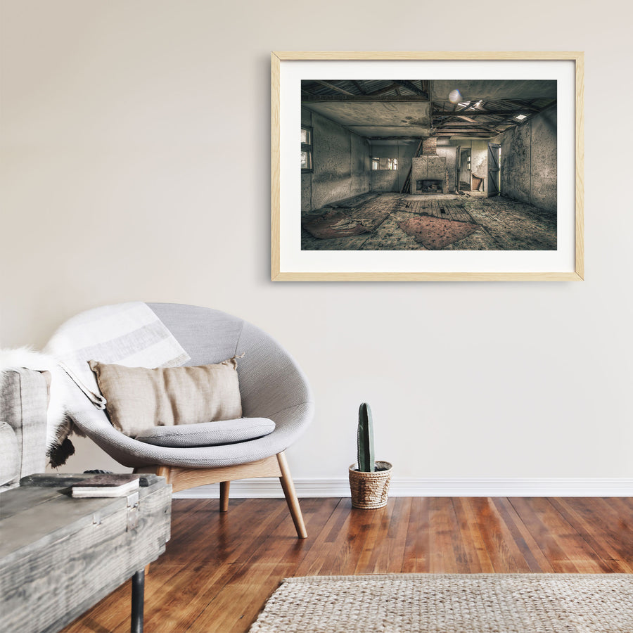A rendered fireplace and brick chimney in a derelict room at Jembaicumbene, with whitewashed walls, a debris-strewn timber plank floor, and partly exposed roof framing overhead.