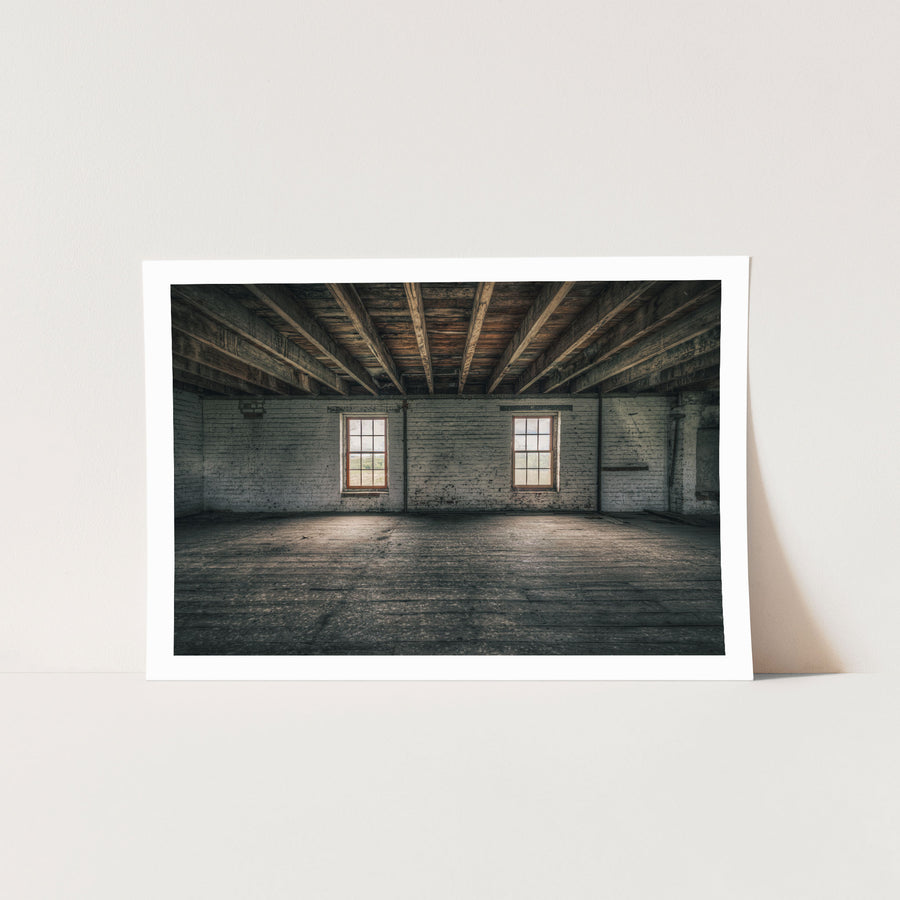 Upper room at Jembaicumbene grain store, two sash windows in a whitewashed brick wall under timber beams.
