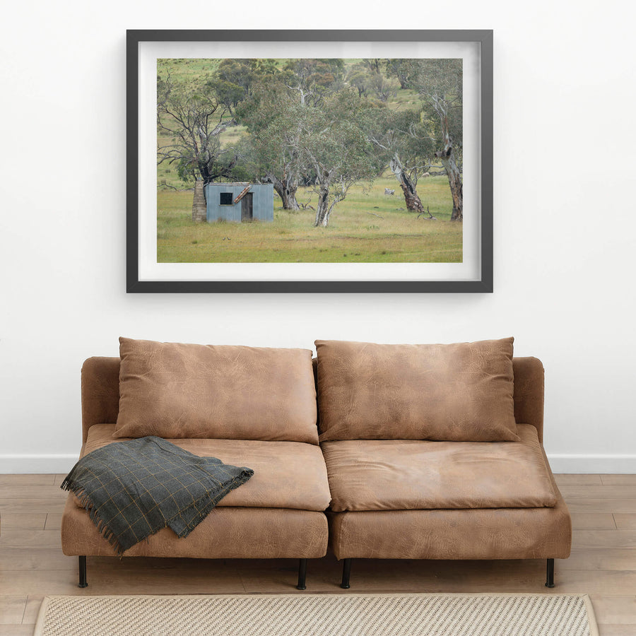 Home Amongst The Gums at A Place to Call Home, a small corrugated iron hut sits low in open grassland, backed by a scatter.