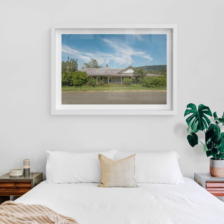 Hunter Hiding at A Place to Call Home, a weatherboard farmhouse sits back from the road edge, half-swallowed by dense green.