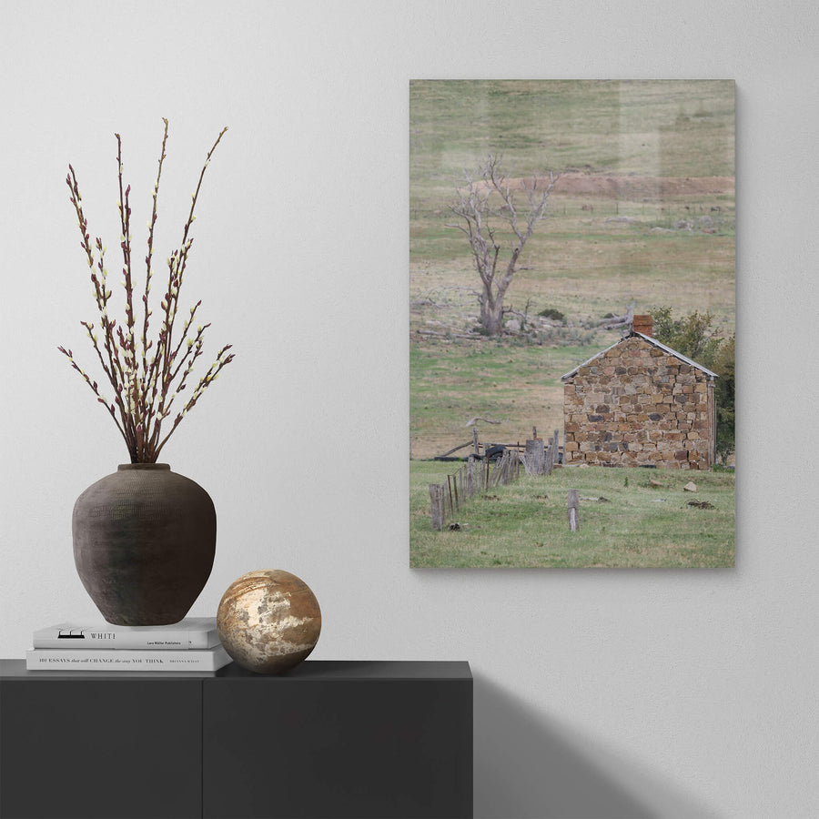Jindabyne Hut at A Place to Call Home, a stone cottage sits low in open pastoral land near Jindabyne.