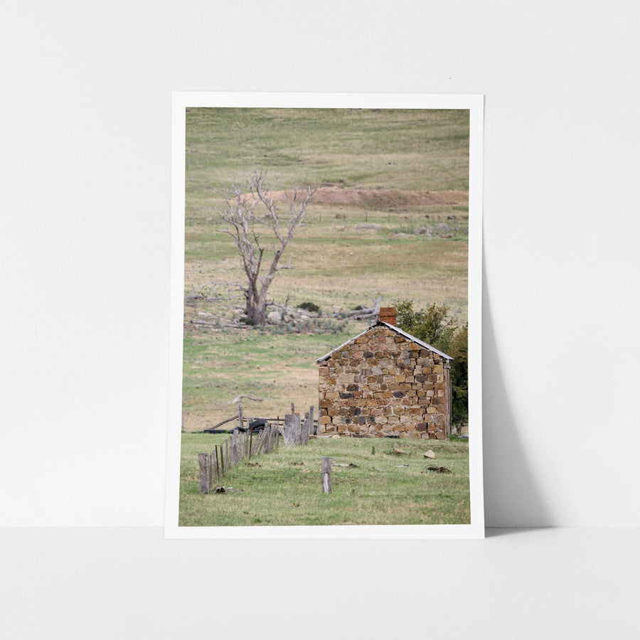 Jindabyne Hut at A Place to Call Home, a stone cottage sits low in open pastoral land near Jindabyne.