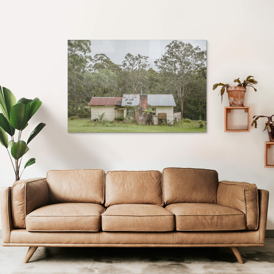 Lochview Cottage at A Place to Call Home, a small weatherboard cottage sits low in a flat green clearing, backed by dense.