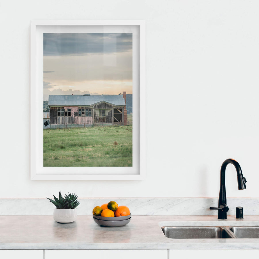 Matong Hut at A Place to Call Home, a weatherboard farmhouse sits low in open green paddock.