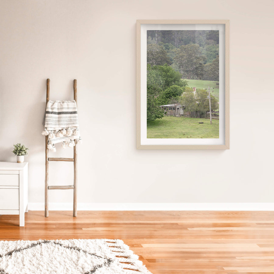 Reclaimed Home at A Place to Call Home, a weatherboard farmhouse sits low in a valley of green pasture, half-swallowed.