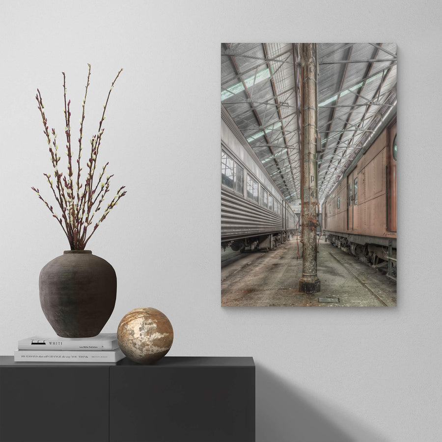 Forecourt at Eveleigh Paint Shop, to the left, the stainless-steel body of Interurban trailer TF6013 reflects the muted industrial light, its corrugated panels and riveted seams built for durability.