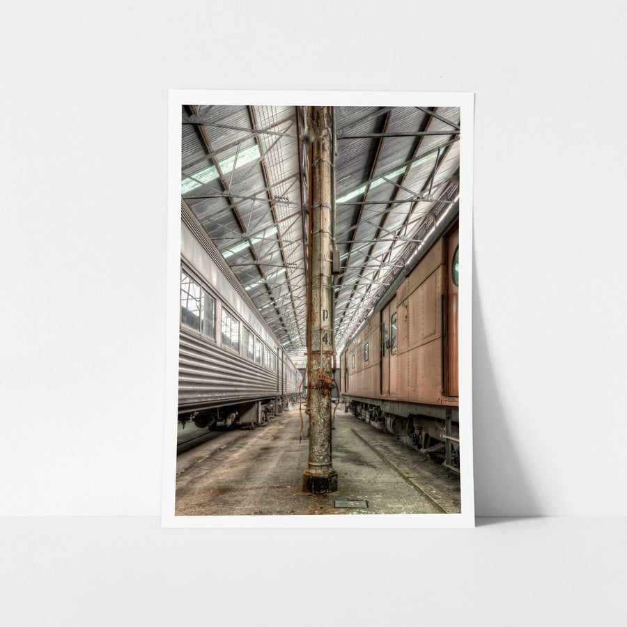 Forecourt at Eveleigh Paint Shop, to the left, the stainless-steel body of Interurban trailer TF6013 reflects the muted industrial light, its corrugated panels and riveted seams built for durability.