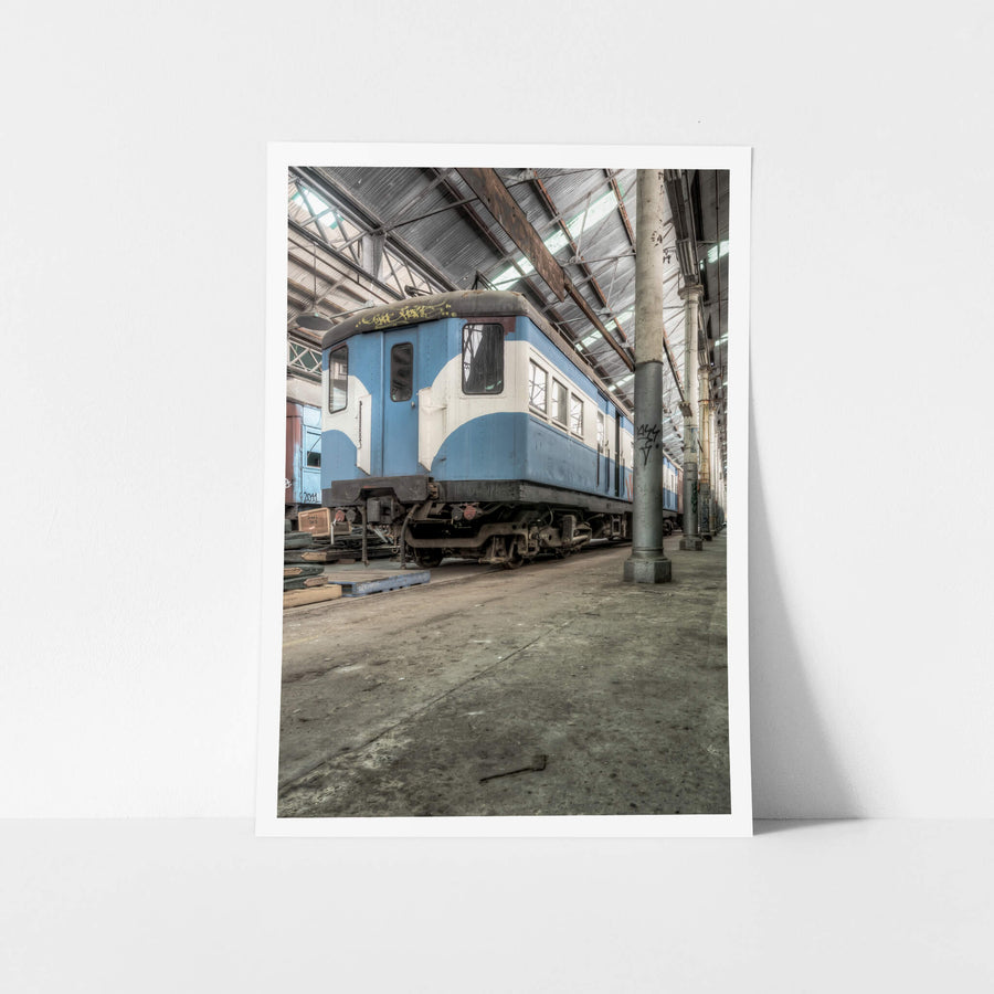 Phillip Shirley at Eveleigh Paint Shop, a blue and white railway carriage sits on bare concrete inside the Eveleigh Paint Shop.