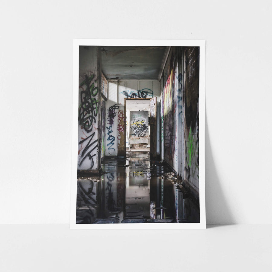 Reflections at Geelong B Power Station, standing water covers the corridor floor, black and still enough to mirror.