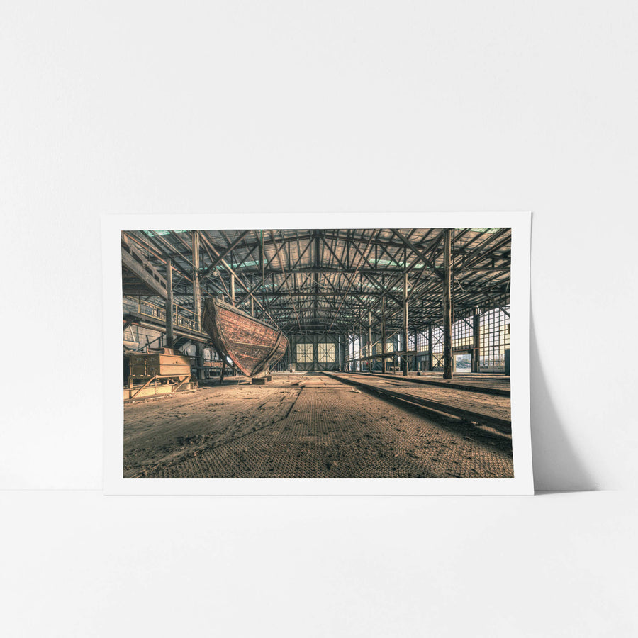 Checkerplate at Halvorsens Boat Yard, a timber hull sits propped on blocks inside a vast industrial shed.