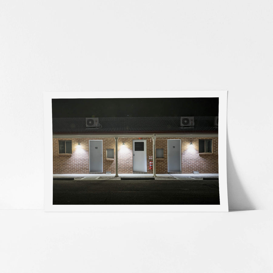 Bushmans Motor Inn at Hotel Motel 101, brown brick facade, single storey, shot dead-on at night.