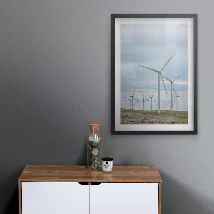 Cluster at Landscapes, white steel towers rise from low, green-brown pastureland under a flat grey sky.