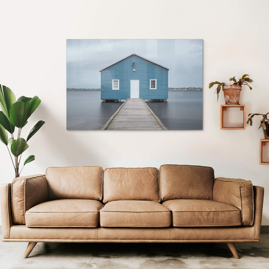 Crawley Edge Boatshed at Landscapes, a single blue timber boatshed sits on steel piles over flat grey water.