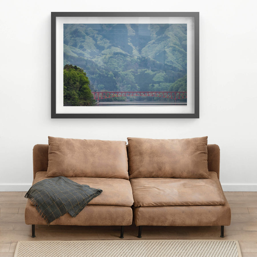Kusaki Dam Lake at Landscapes, a red steel bridge dwarfed by mountains stretches over a lake.
