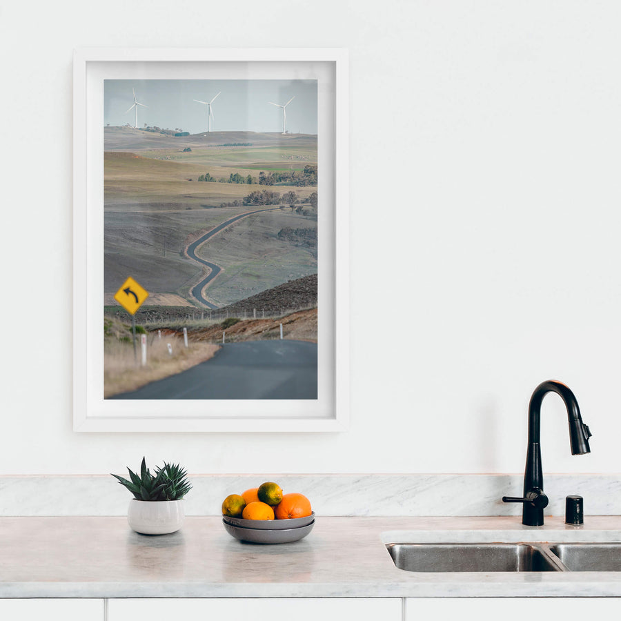 The Snowy River Way at Landscapes, a single lane of asphalt cuts through open grazing country, snaking down into a valley.