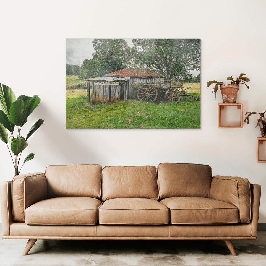 Backyard at Leichhardt House, a weathered timber slab building sits low in green pasture.