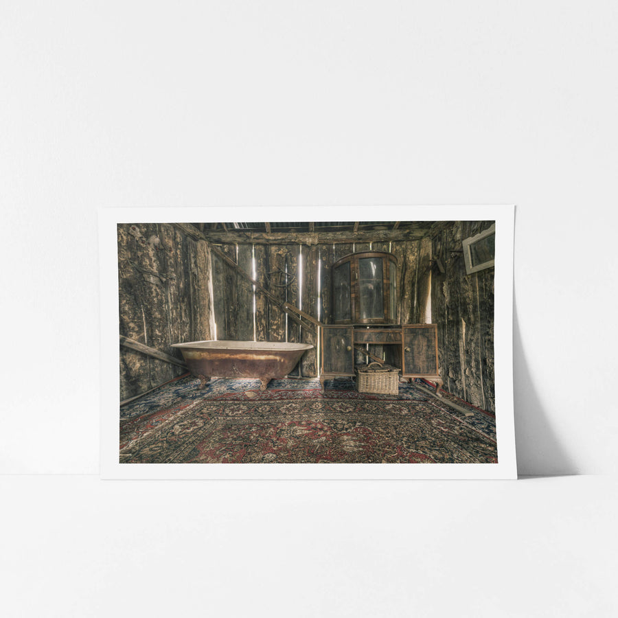 Bath at Leichhardt House, a cast-iron clawfoot bathtub sits on a Persian rug, its enamel interior stained brown with rust.