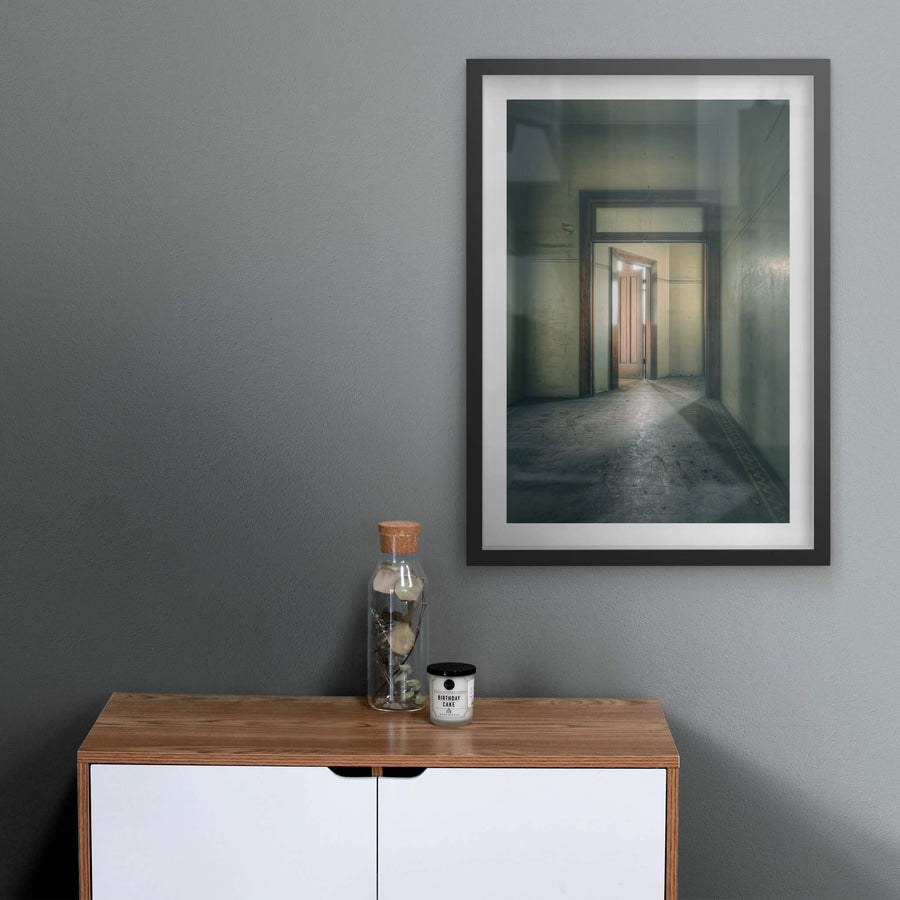 Enclave at Lewisham Hospital, a narrow corridor leads to a timber door, half-open, light pressing through the gap.