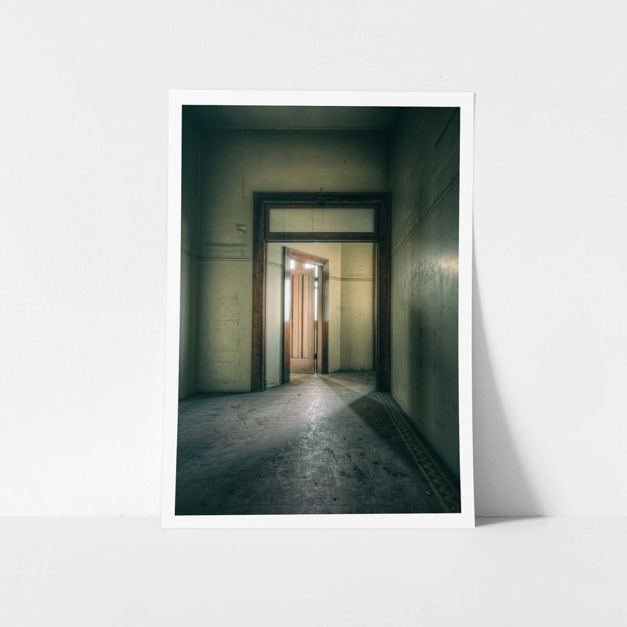 Enclave at Lewisham Hospital, a narrow corridor leads to a timber door, half-open, light pressing through the gap.