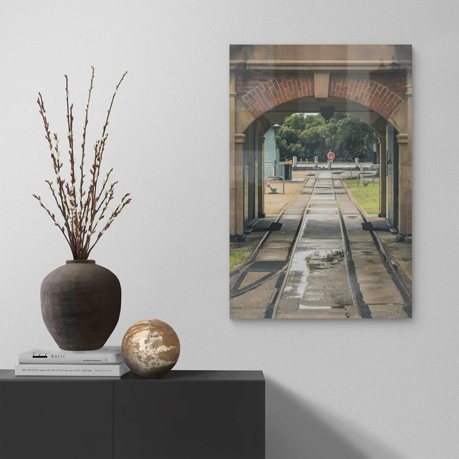 Entrance Rails at Newington Armory, narrow-gauge rail tracks run wet through a sandstone and brick archway, heading.