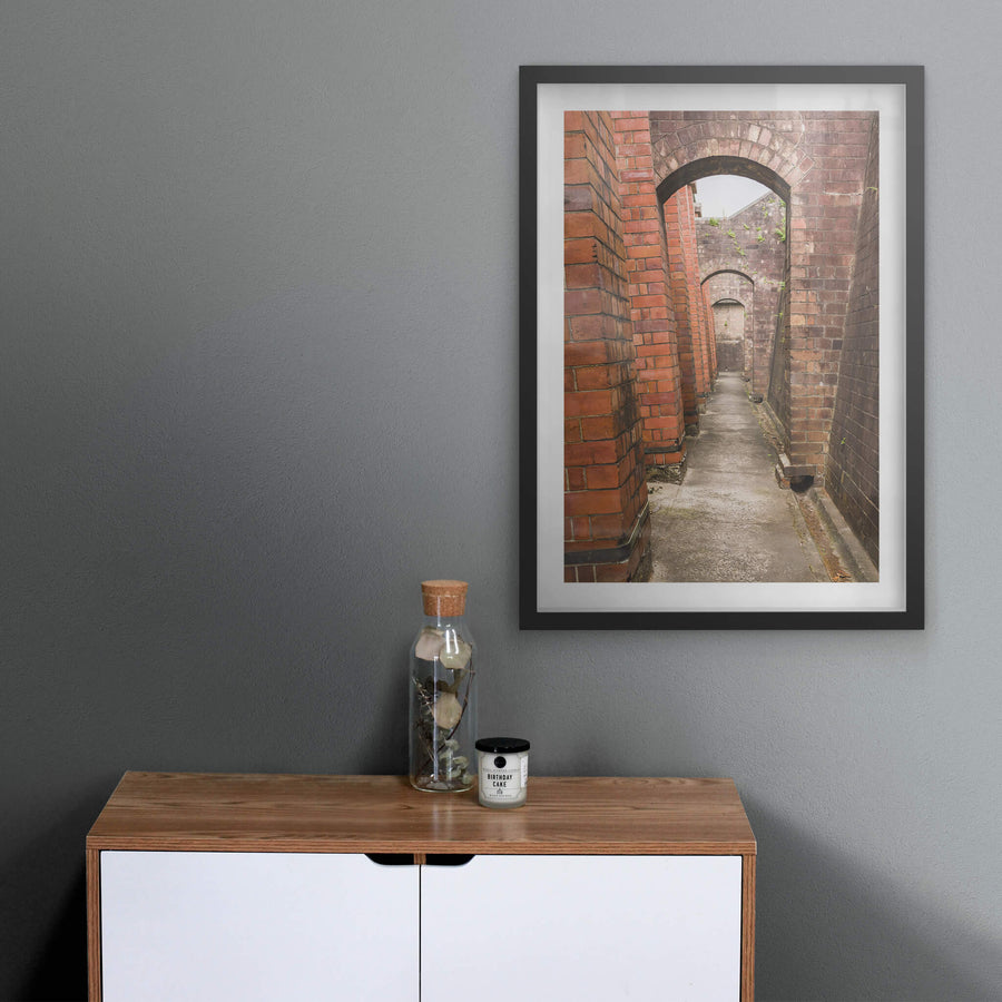 Magazine Exterior Path at Newington Armory, a narrow concrete path runs between two massive brick walls.