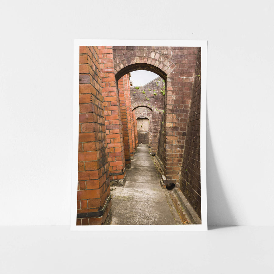 Magazine Exterior Path at Newington Armory, a narrow concrete path runs between two massive brick walls.