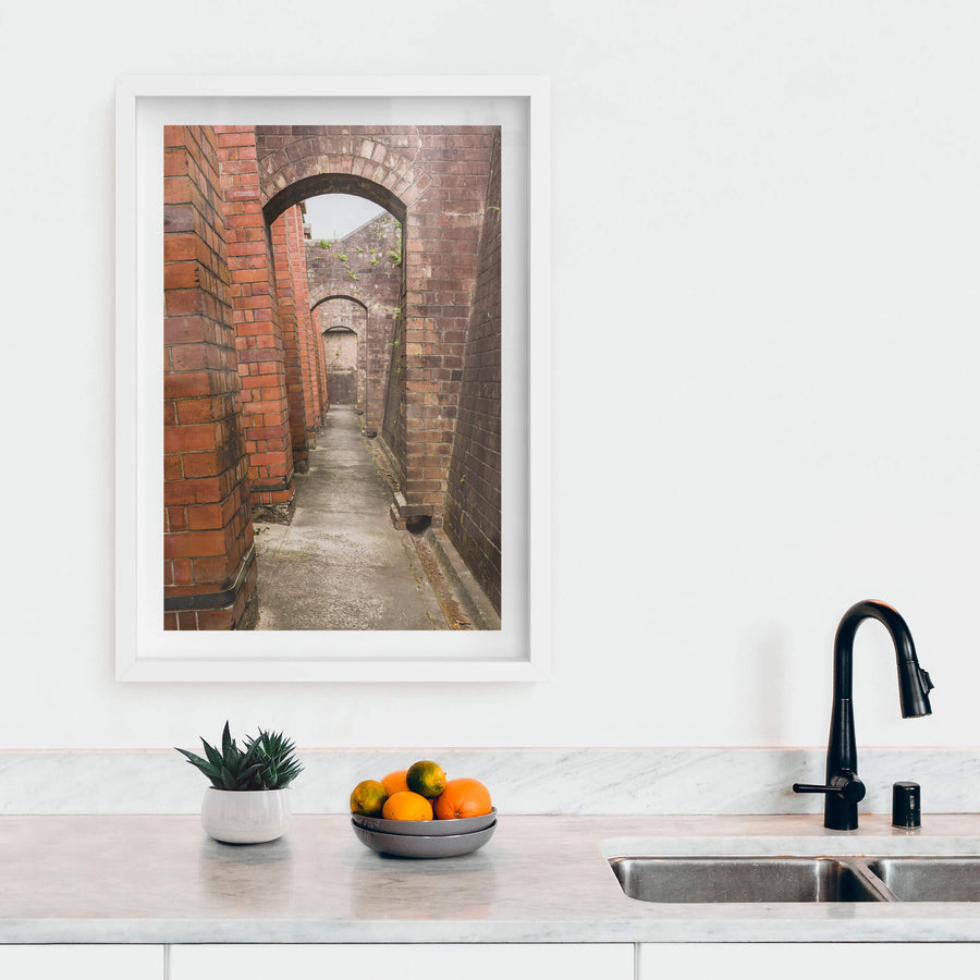 Magazine Exterior Path at Newington Armory, a narrow concrete path runs between two massive brick walls.