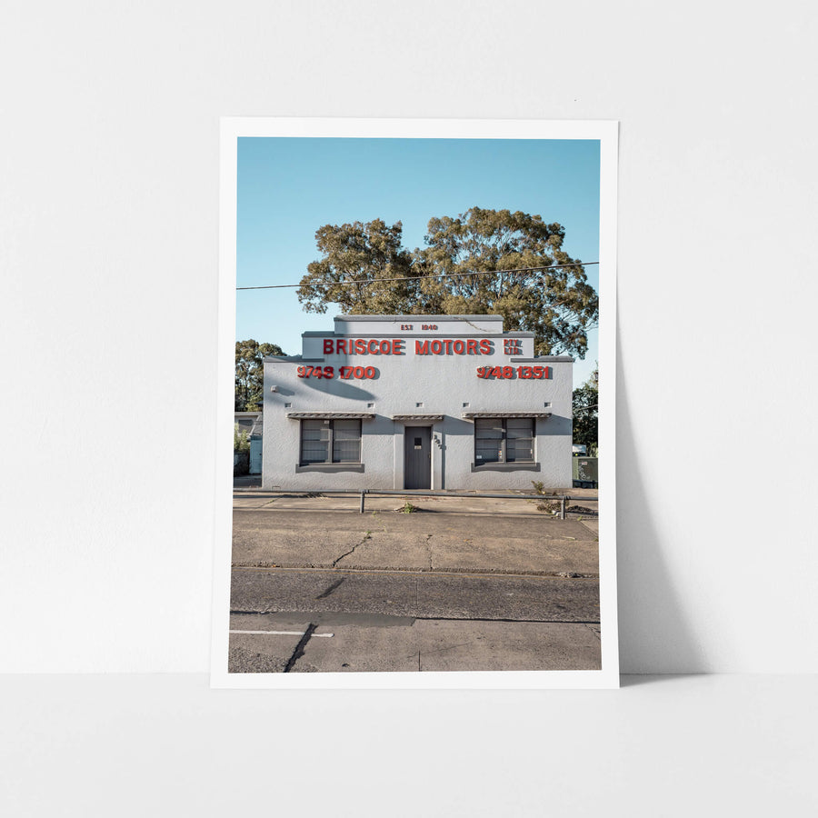Briscoe Motors at Parramatta Road, a white rendered Art Deco façade sits square to the street.
