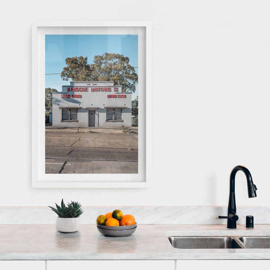 Briscoe Motors at Parramatta Road, a white rendered Art Deco façade sits square to the street.