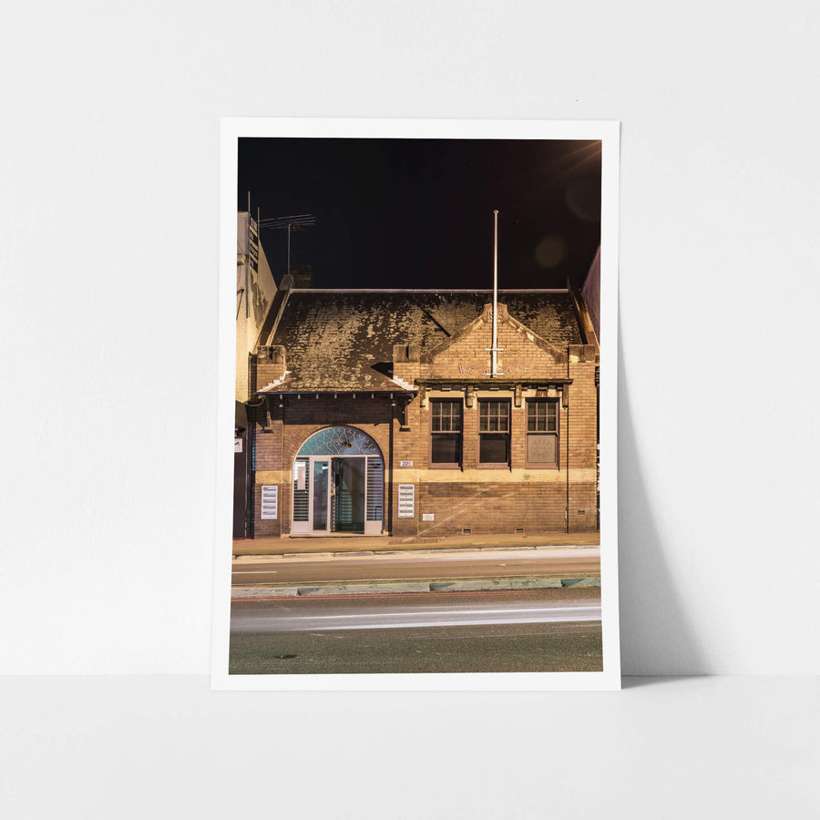 Westgate Post Office at Parramatta Road, brown brick facade on Parramatta Road, lit warm against a black sky.