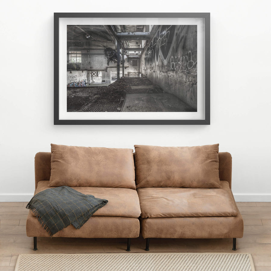 Concentrate Room Mezzanine at Peters Ice Cream Factory, a heavy motor assembly hangs from a steel I-beam, suspended above a floor thick with compacted debris and dirt.