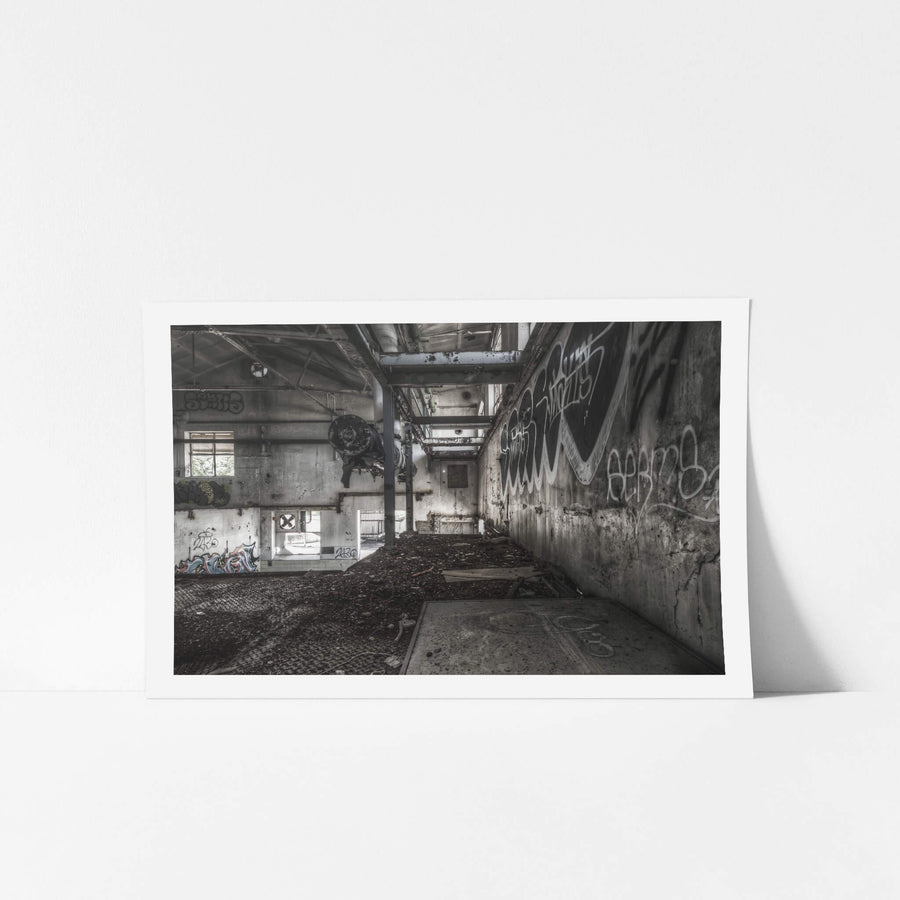 Concentrate Room Mezzanine at Peters Ice Cream Factory, a heavy motor assembly hangs from a steel I-beam, suspended above a floor thick with compacted debris and dirt.