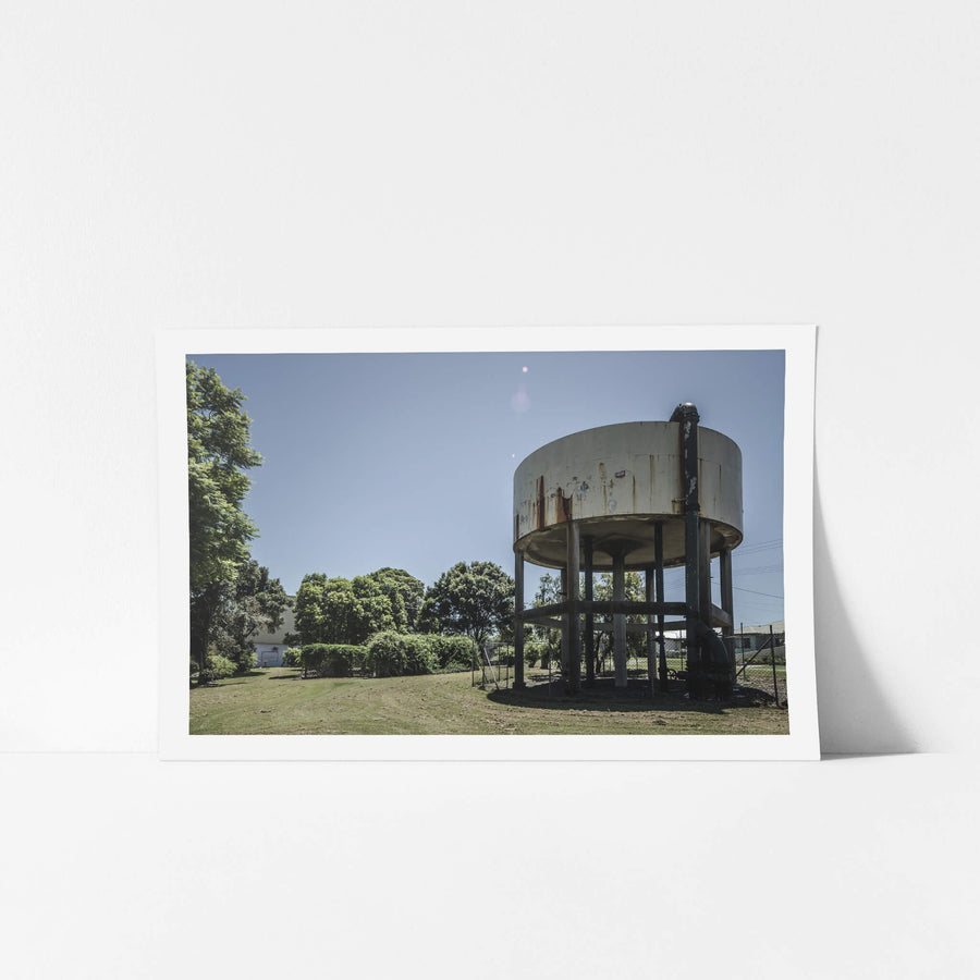 Front Lawn at Peters Ice Cream Factory, a cylindrical steel water tank sits raised on six legs above a mowed front lawn.