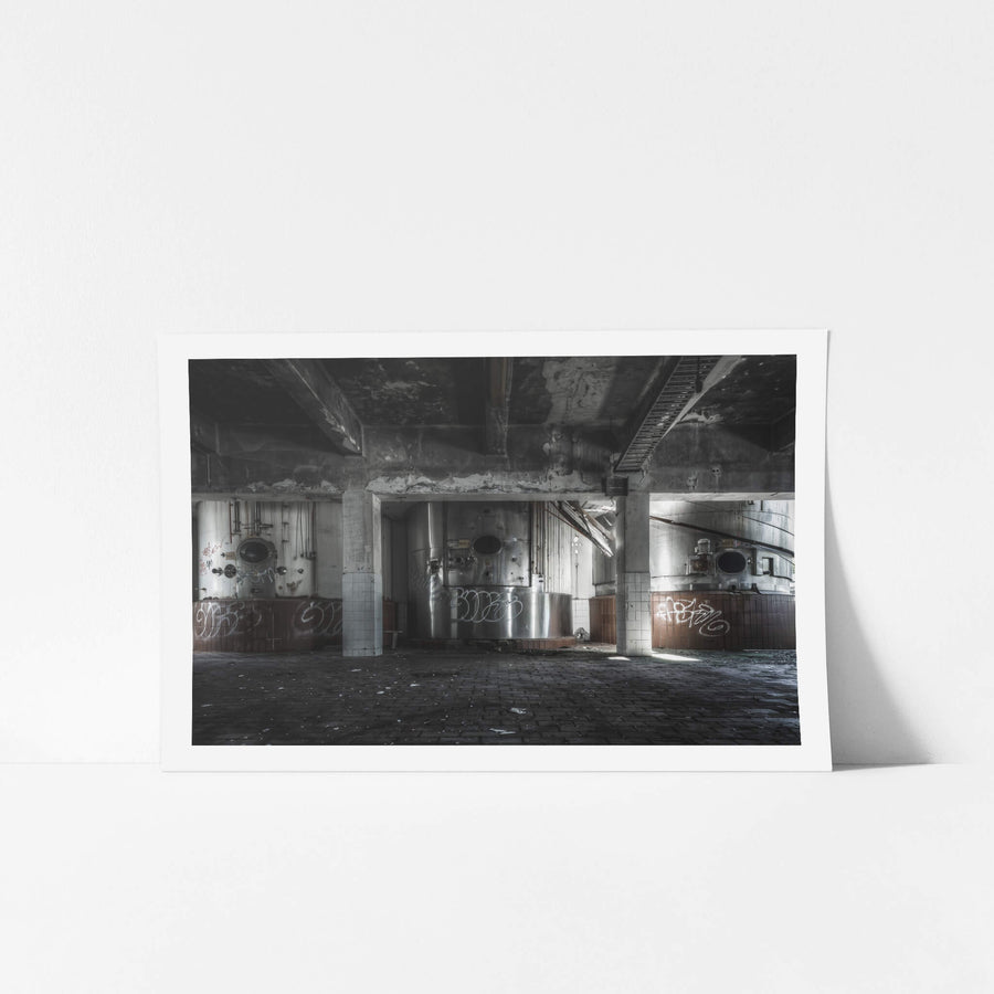 Raw Milk Silos at Peters Ice Cream Factory, stainless steel silos sit in bays divided by concrete columns, their circular hatches dark and open.