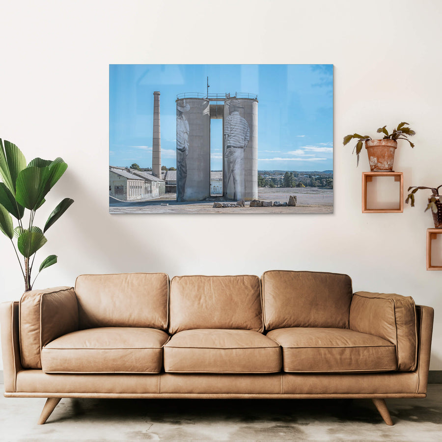 Between Silos at Portland Cement Works, two concrete silos stand side by side on bare ground, a narrow vertical gap cut.