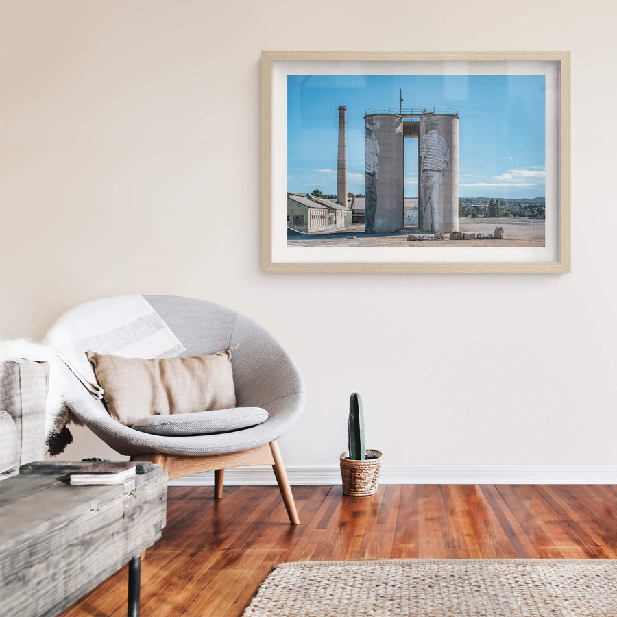 Between Silos at Portland Cement Works, two concrete silos stand side by side on bare ground, a narrow vertical gap cut.