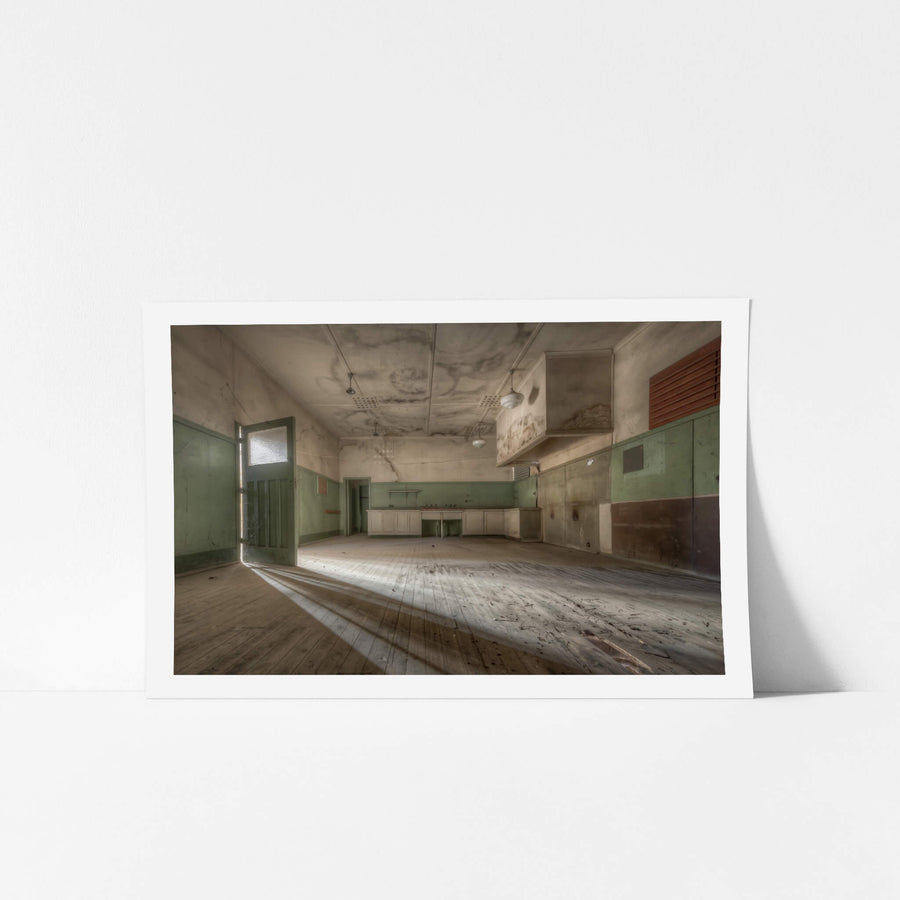 Kitchen at Portland Cement Works, low afternoon light cuts through a doorway and stretches across bare timber floorboards.