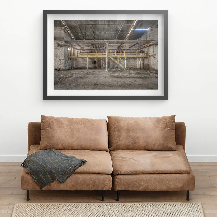 Pipework at Portland Cement Works, a yellow steel mezzanine spans the width of the building, its walkway and staircase.