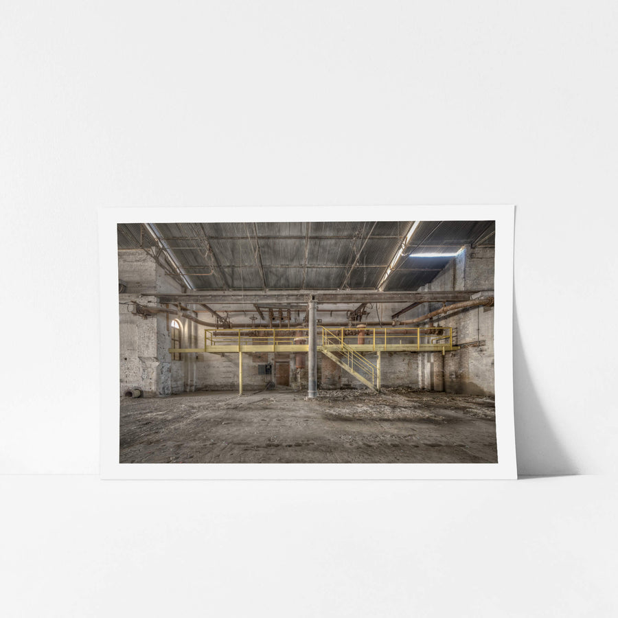 Pipework at Portland Cement Works, a yellow steel mezzanine spans the width of the building, its walkway and staircase.