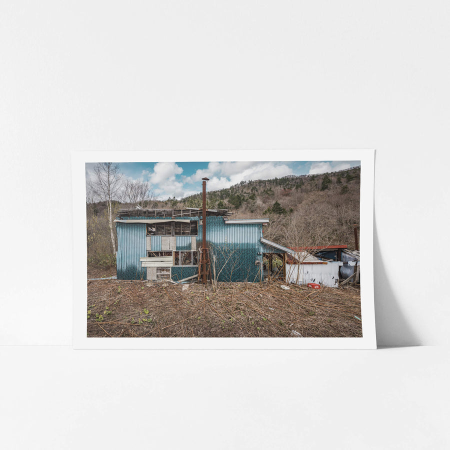 Collapsed House at Streetscapes of Yubari, blue corrugated iron cladding covers the front face of a small two-storey.