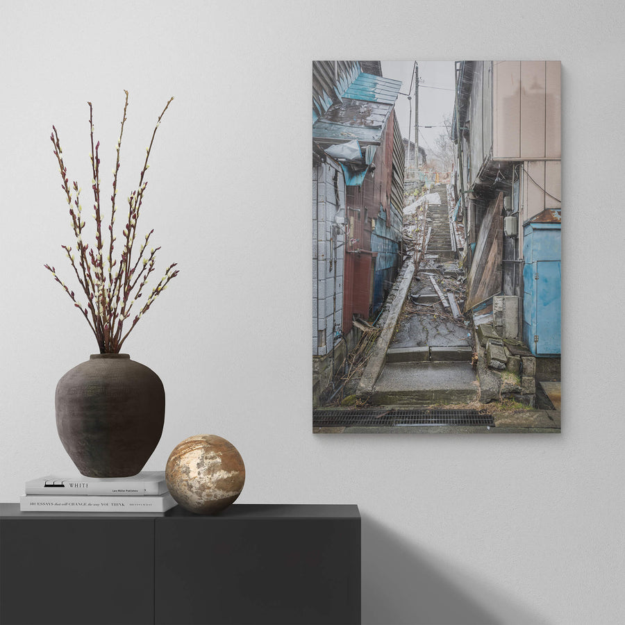 Stairway at Streetscapes of Yubari, a narrow concrete stairway climbs steeply between tightly packed buildings.