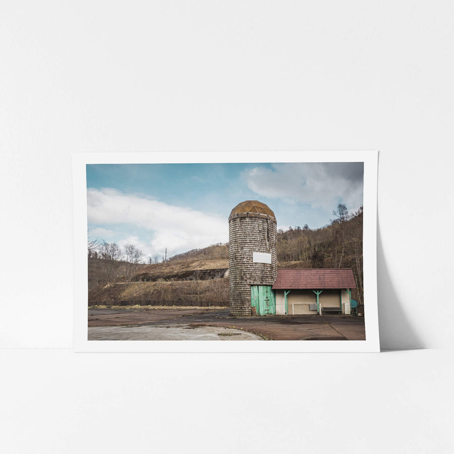Ticket Centre at Streetscapes of Yubari, a wooden shingle silo rises from the concrete, capped with a faceted copper dome.
