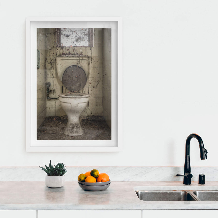 Toilet at Terminus Hotel, a white ceramic pedestal toilet sits centred in a narrow tiled cubicle.