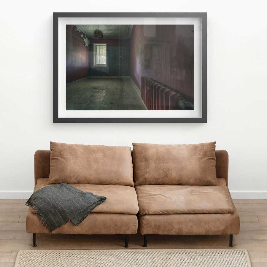 Heater at The Asylum, a cast-iron column radiator sits against the far wall, painted the same deep oxblood as the room.