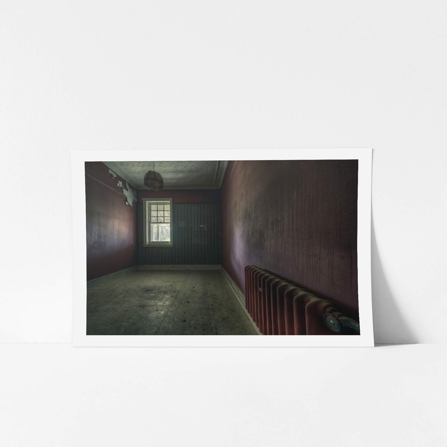 Heater at The Asylum, a cast-iron column radiator sits against the far wall, painted the same deep oxblood as the room.