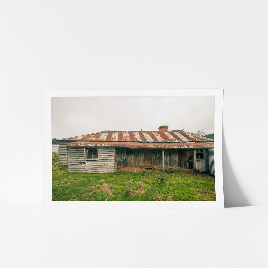 Front Yard at The Post Office, a low-slung timber homestead sits under a corrugated iron roof mottled with rust.