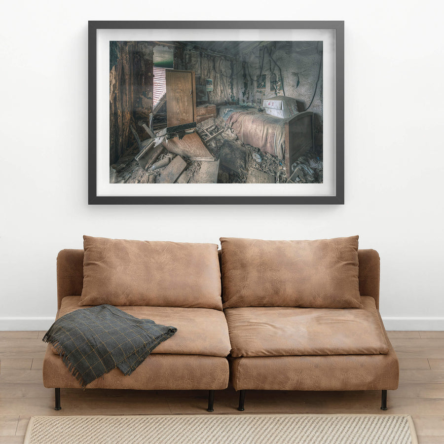 Life As It Was at The Post Office, a single bed sits against the back wall, a faded pink blanket still draped.