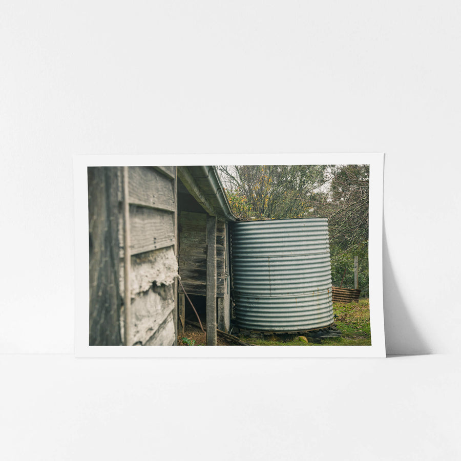 Water Tank at The Post Office, a corrugated steel water tank sits tight against the back corner of a timber outbuilding.